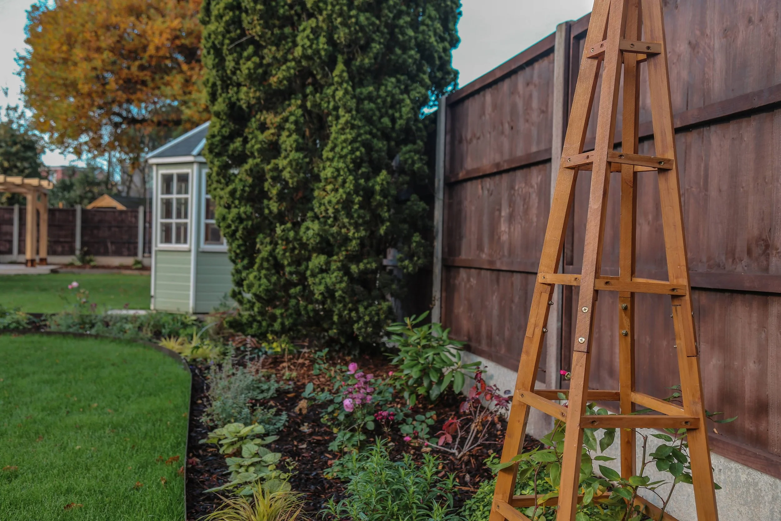 obelisk in a planting bed surrounded by seasonal planting , landscaping in Warwickshire