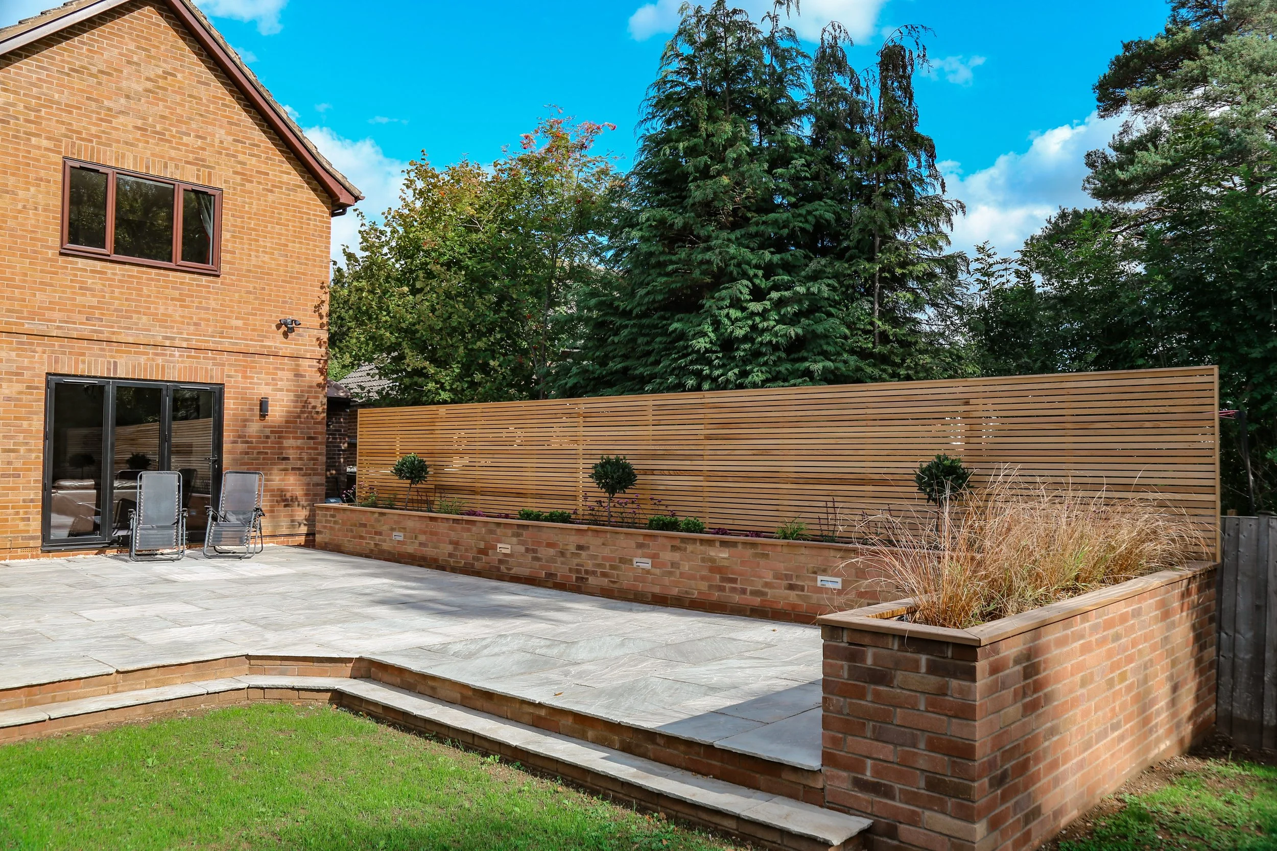 Back garden patio area, using natural stone  paving and a large cedar slatted fence