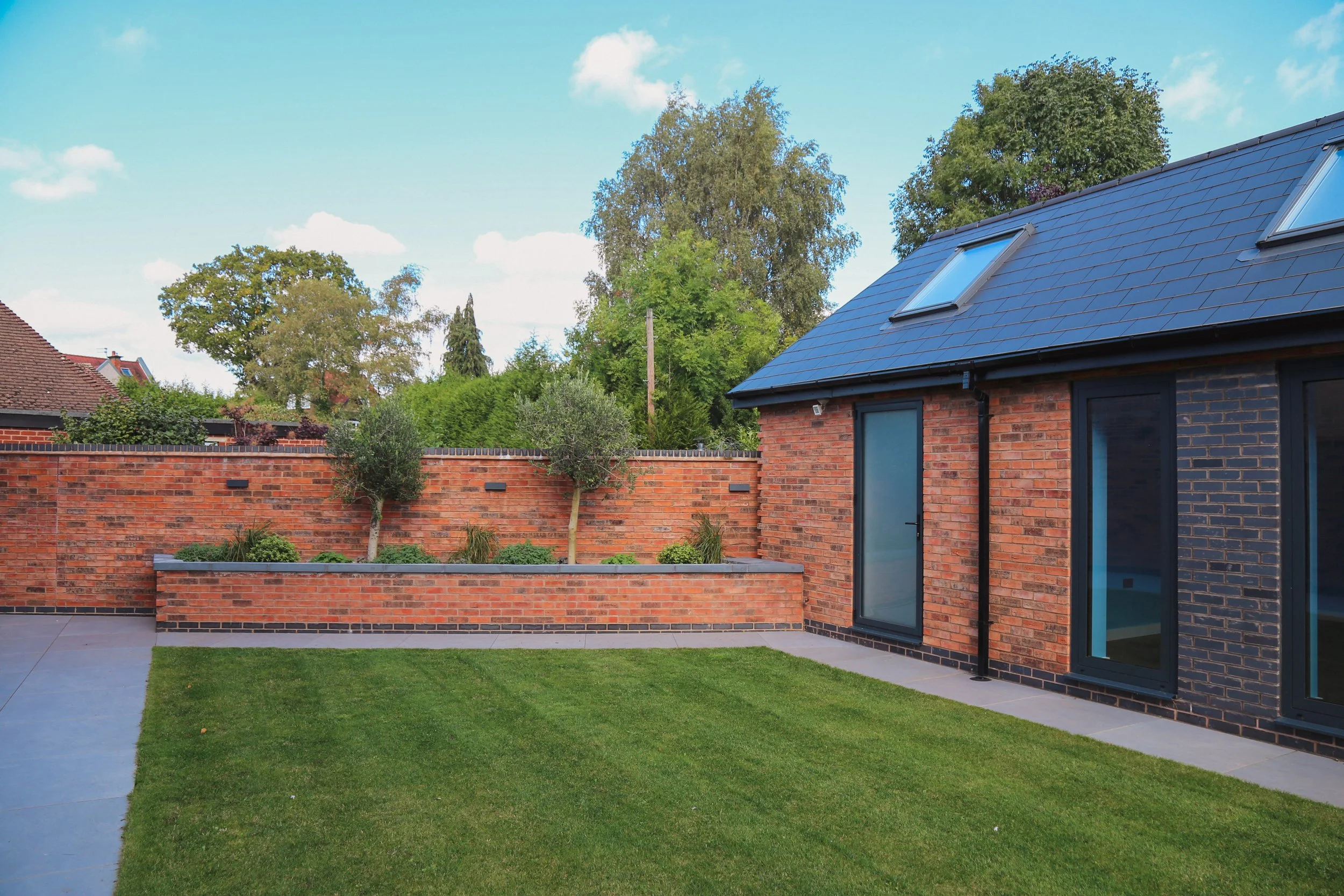 Garden designed to be modern, with raised planting bed, olive trees, straight lines, Modern garden design in Warwickshire