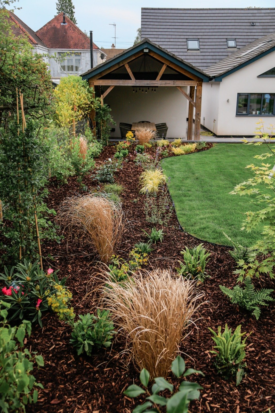 Large planting beds run around the garden bordering the lawn, adding structure to the garden. Bark mulch to prevent weeds growing amongst the planting