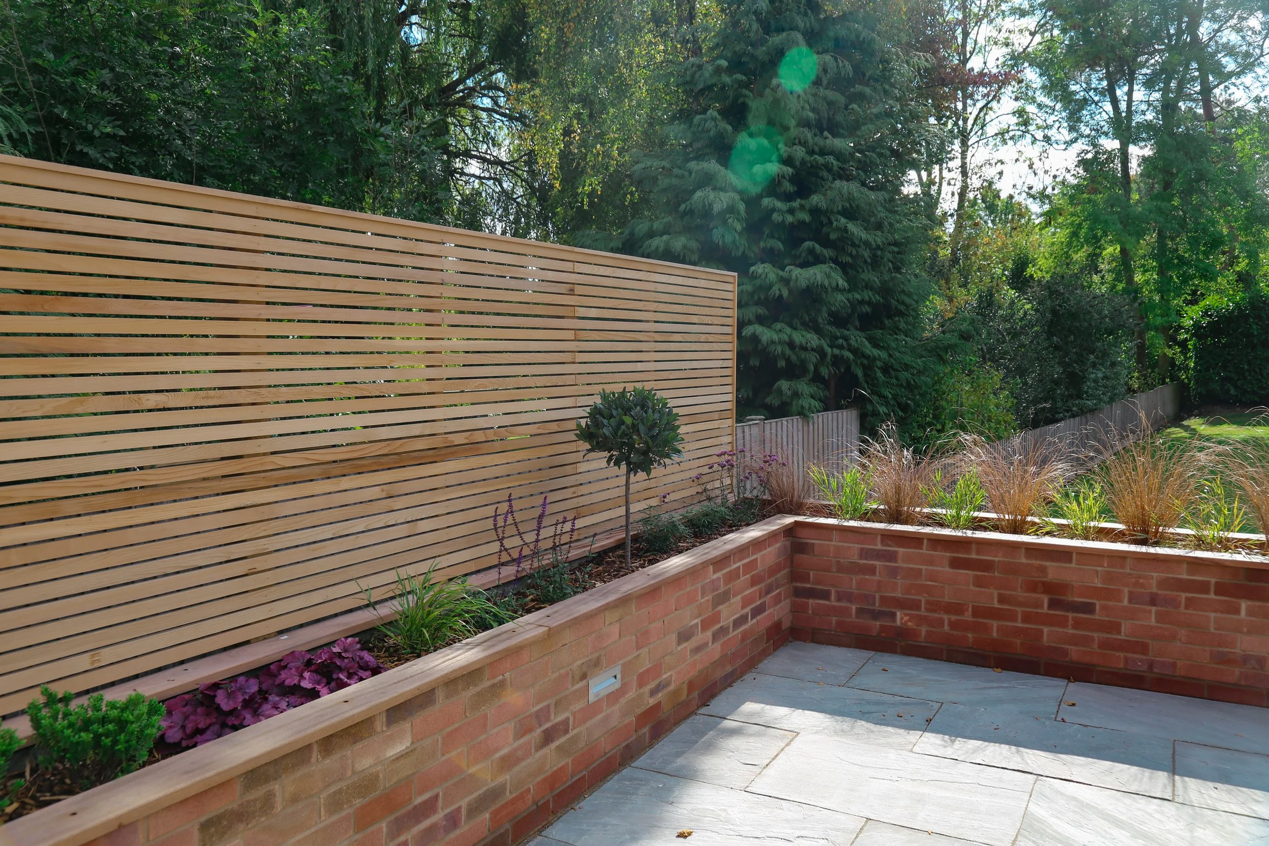 Modern garden, using natural stone sandstone paving, a cedar slat fence is used to create privacy