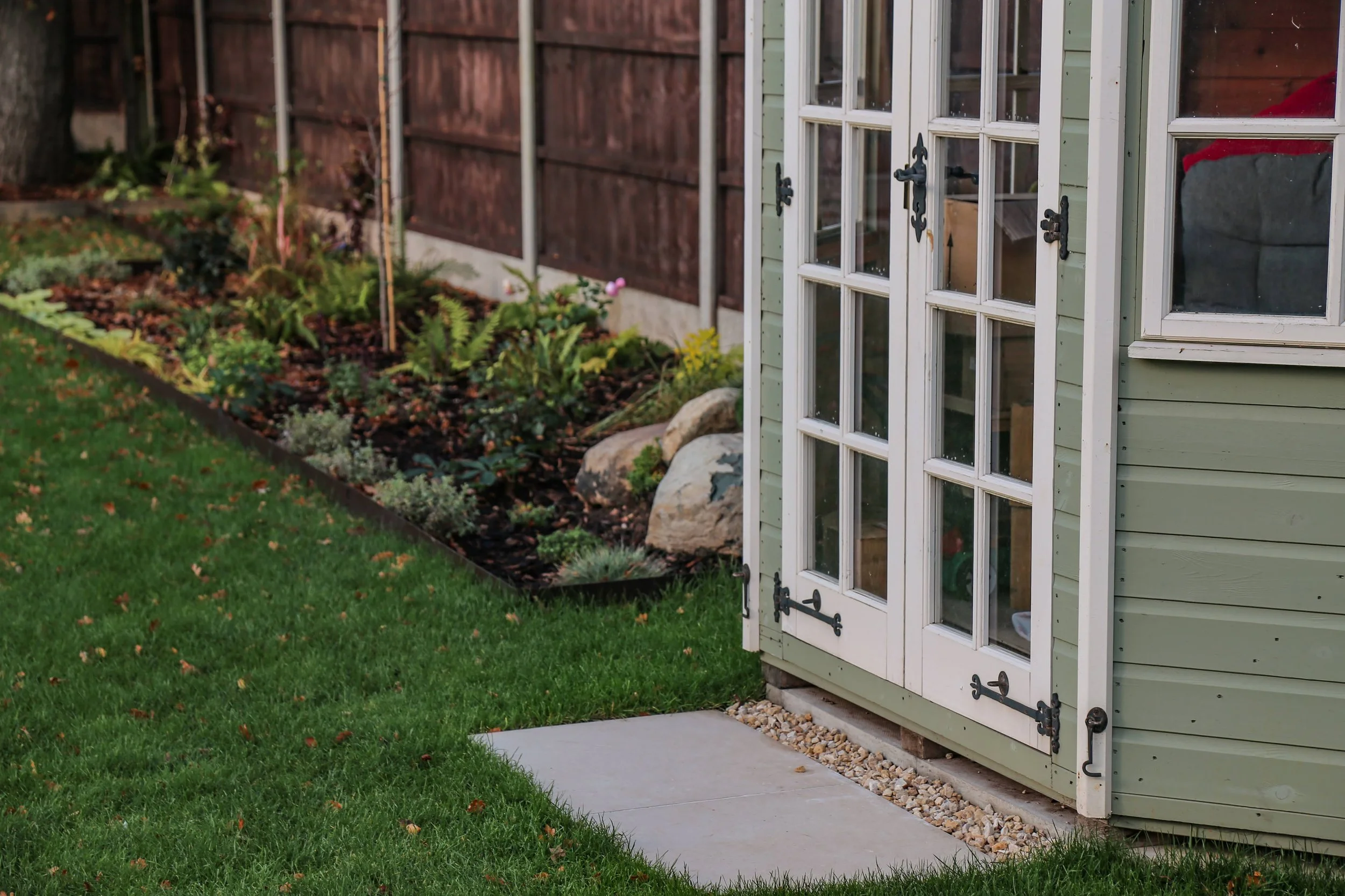 Outdoor garden room sat in planting beds and turf