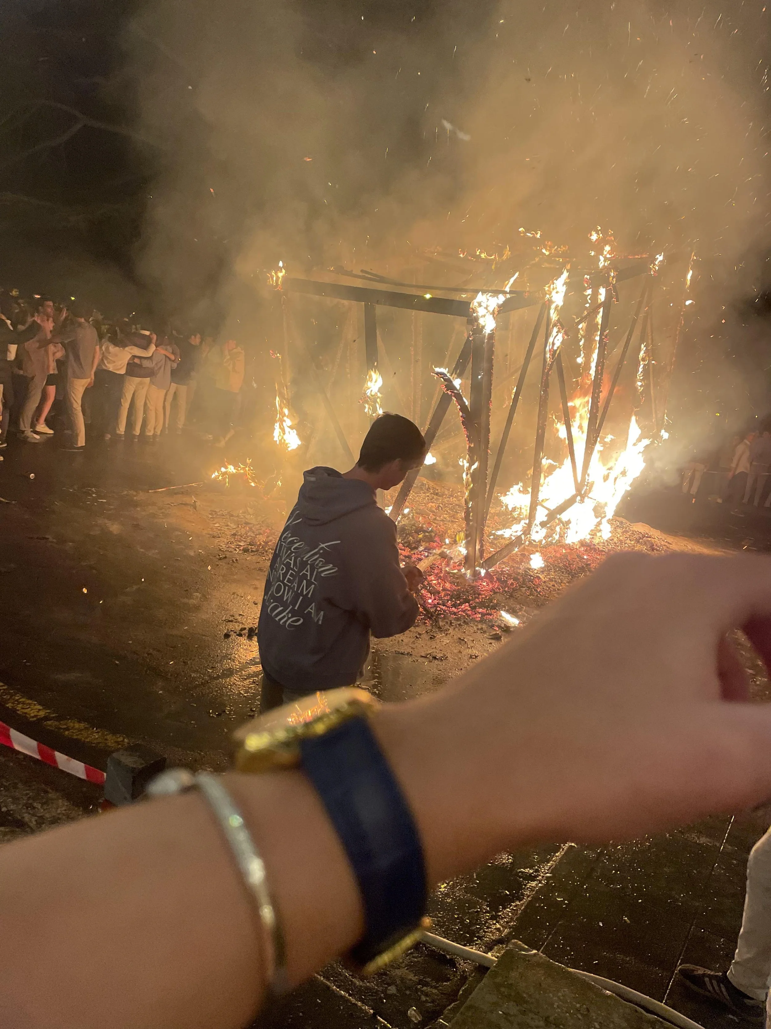 People gathered around a large bonfire during a celebration or event at night.