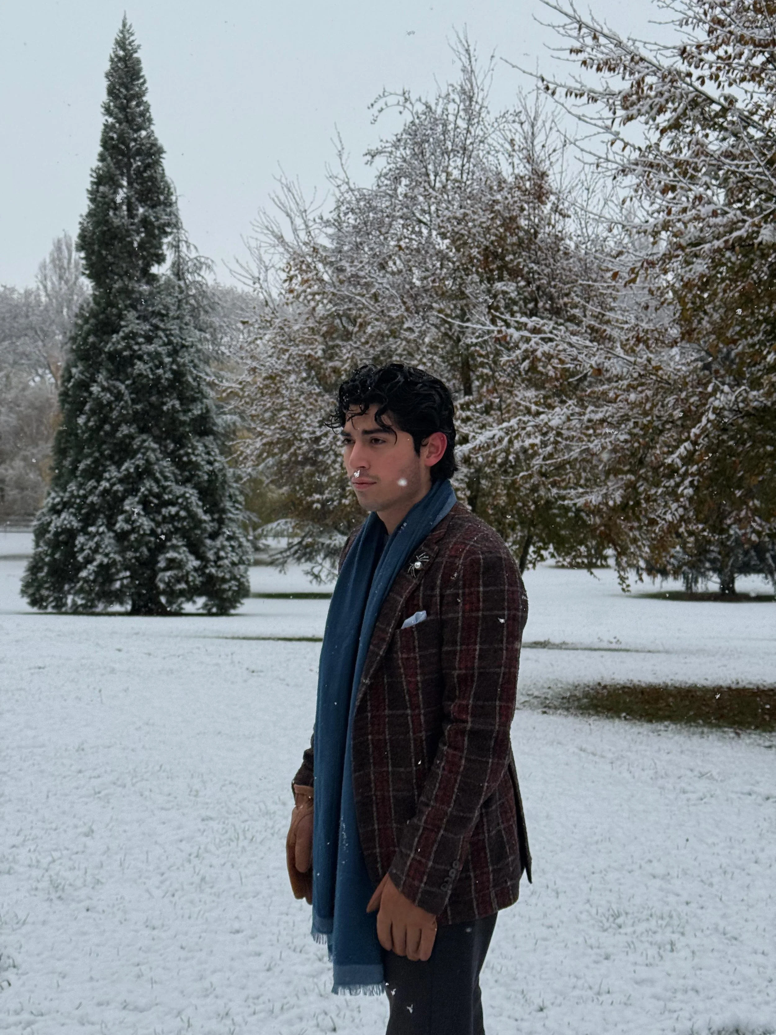 A young man wearing sunglasses and a patterned jacket holding a lit sparkler at a celebration or party in a dark setting.
