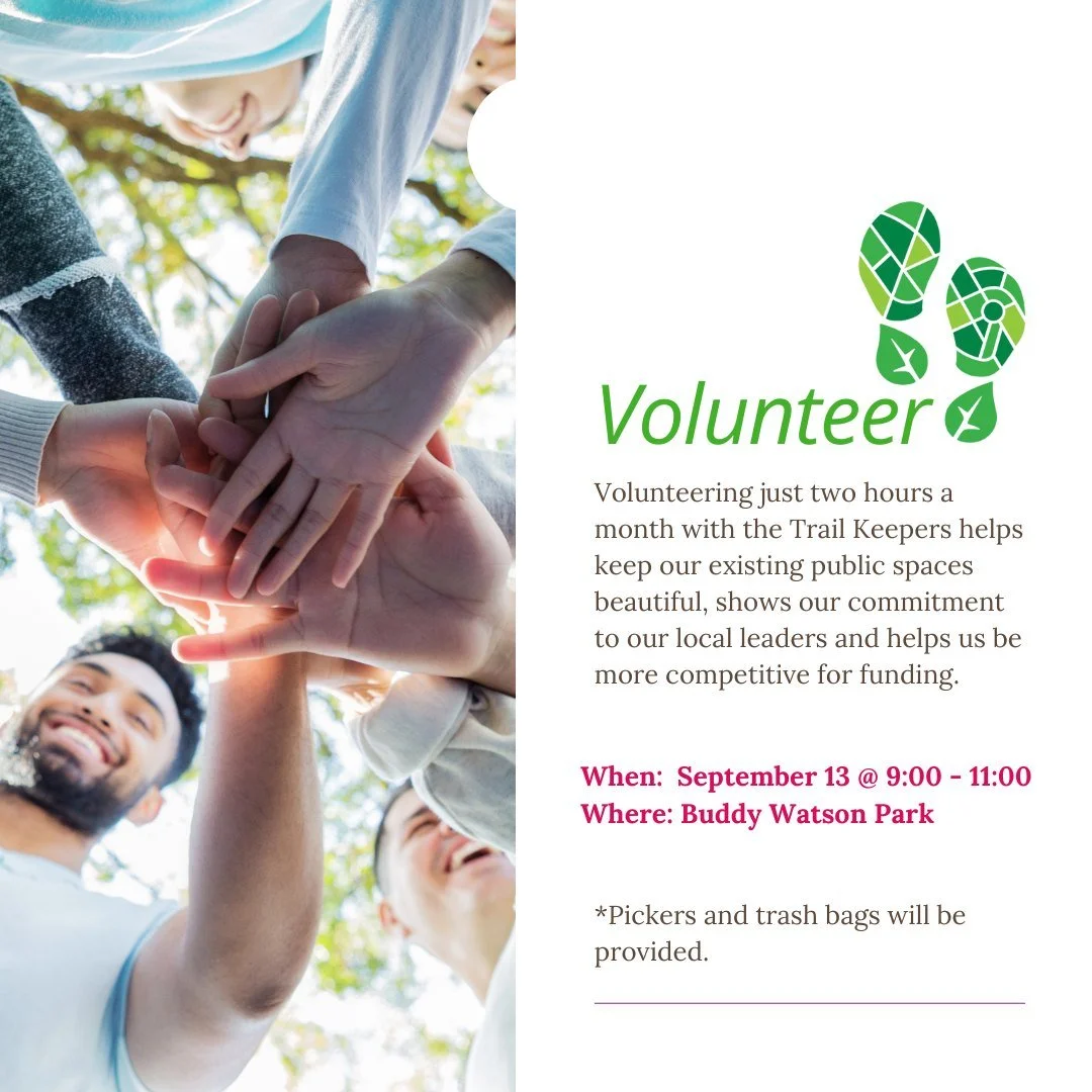 Group of volunteers with hands stacked together outdoors, smiling.