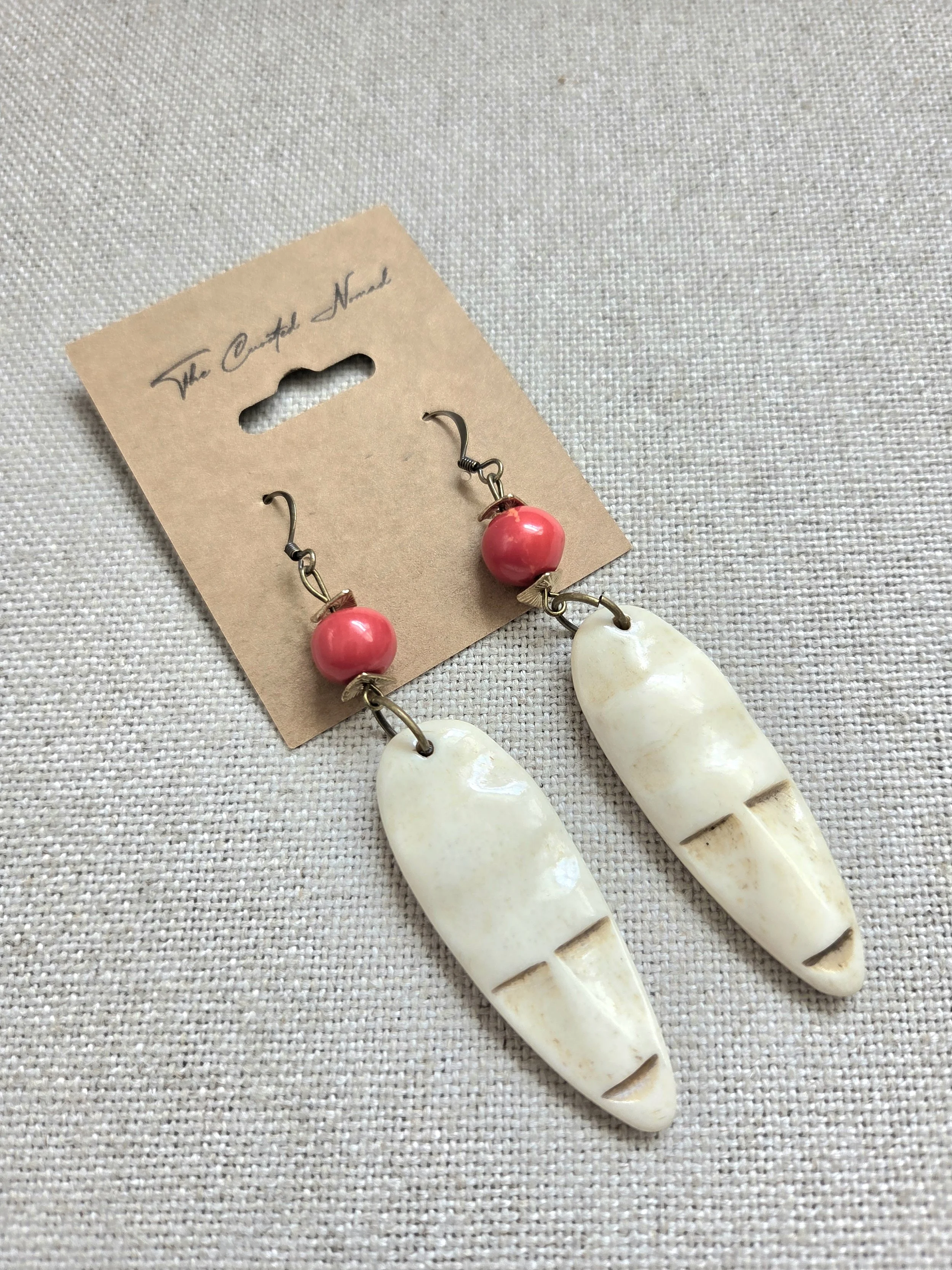 Etched bone face with red ceramic bead