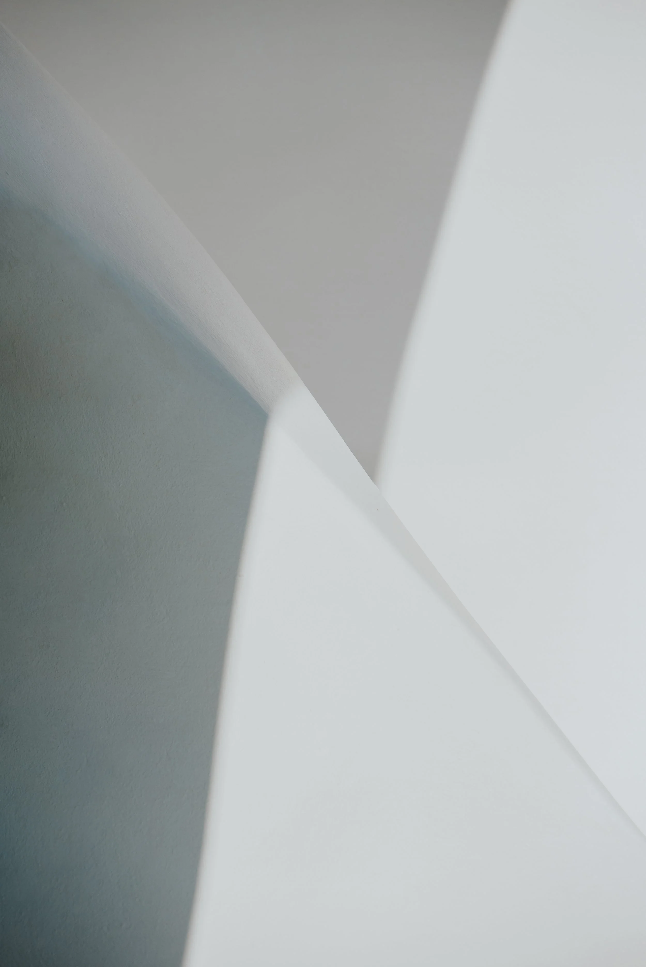 Abstract photo of intersecting smooth white and light gray geometric shapes.