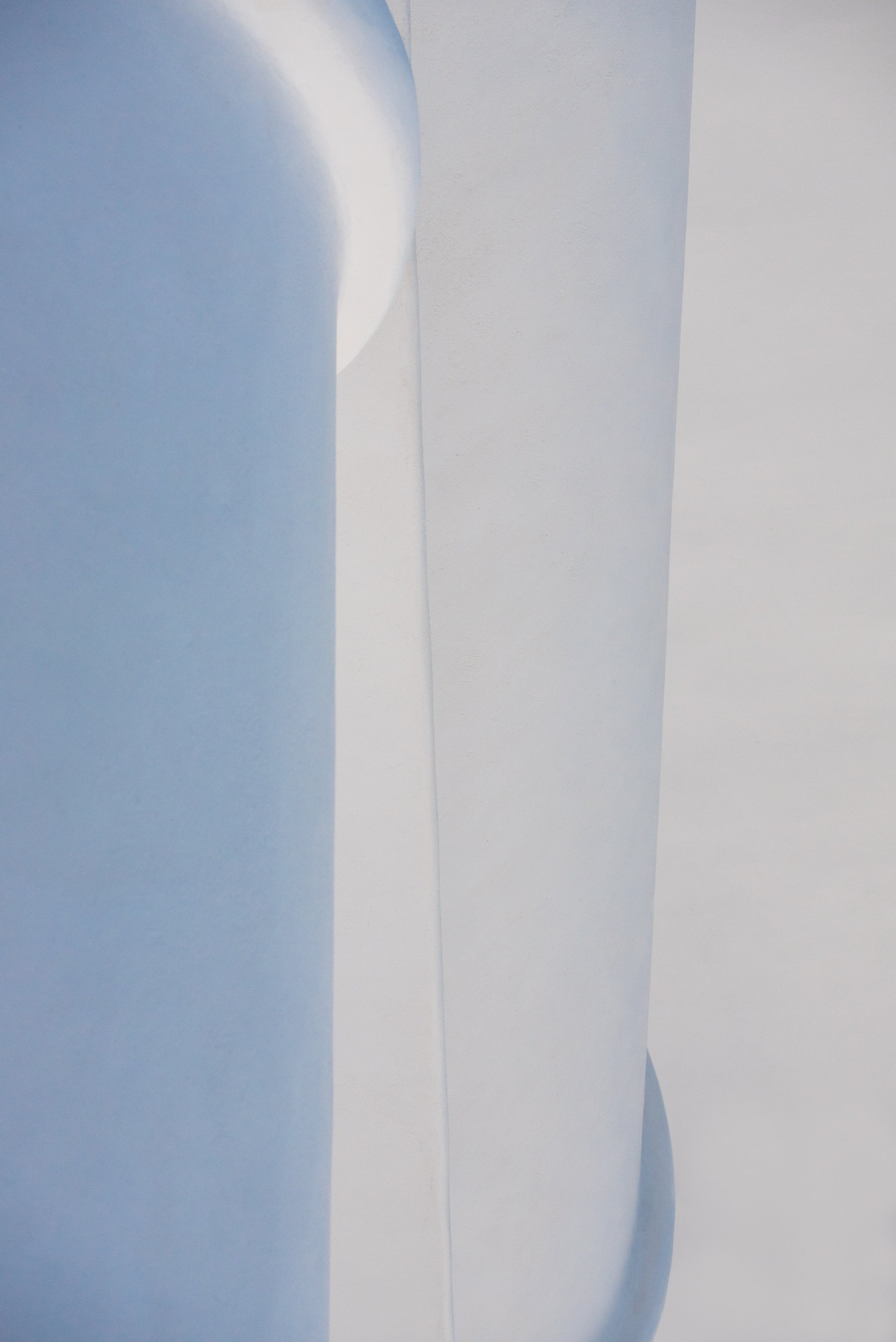 Close-up of a geometric abstract sculpture with smooth, curved surfaces in light blue and white.