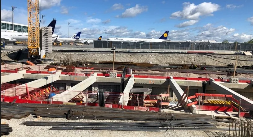 Baustelle mit Bauarbeiten und Flugzeuge am Flugaufnahmepier, darunter Kräne und Baugerüste