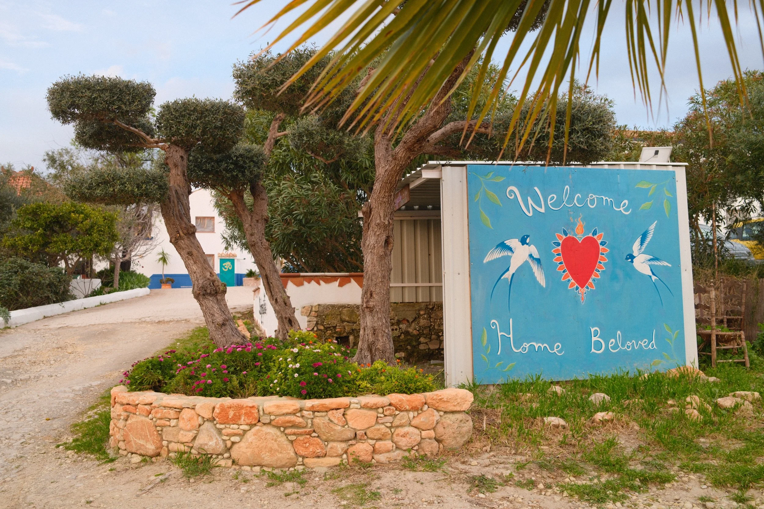 A large blue sign with the words 'Welcome Home Beloved' y. Meala Soul Yoga wellness retreat spain india womens retreat