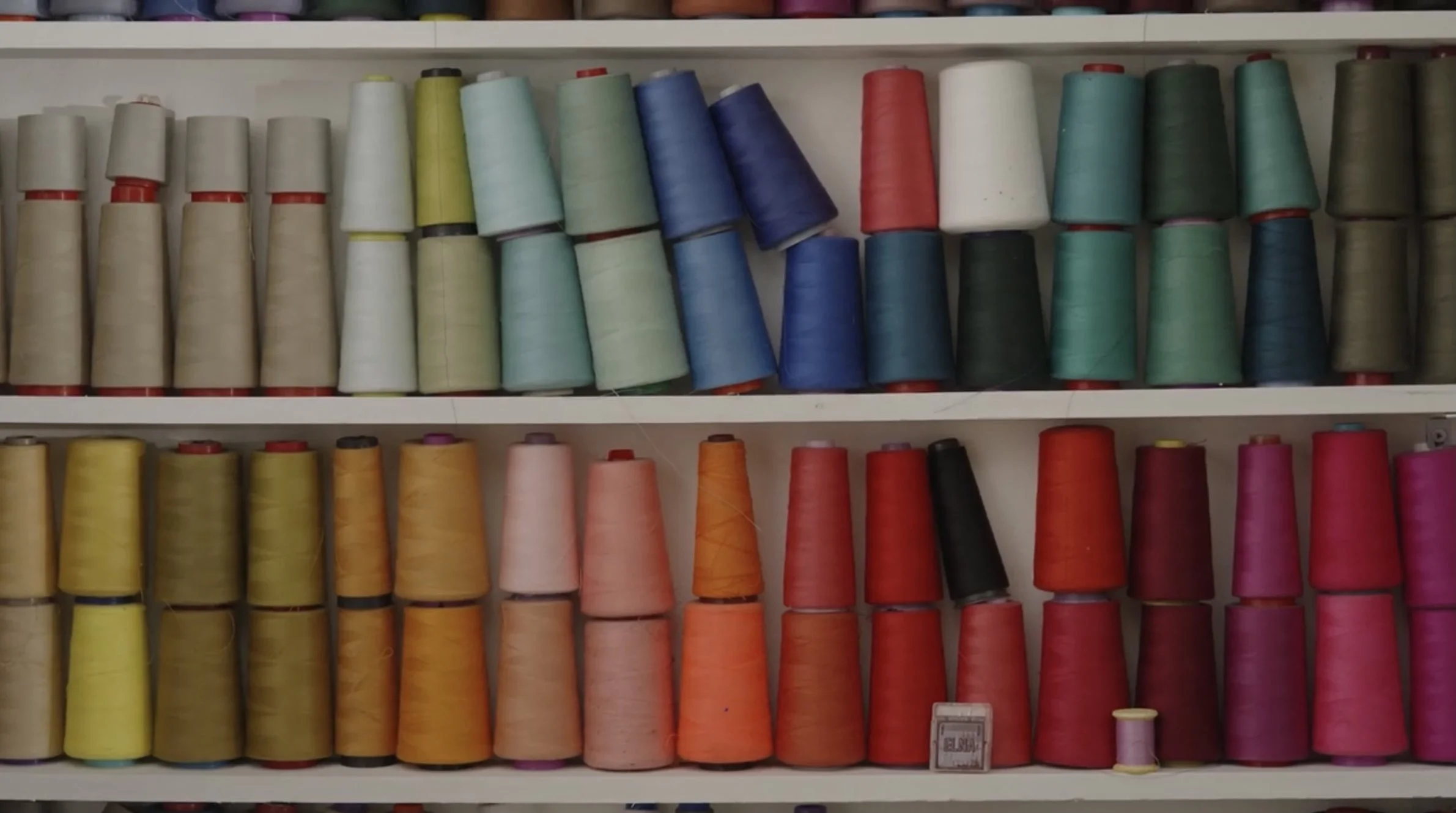Multiple spools of colorful thread on white shelves, arranged in rows. Nourish & Create yoga and creative day retreat in Galway, Ireland with Meala Soul and Mise Tusa