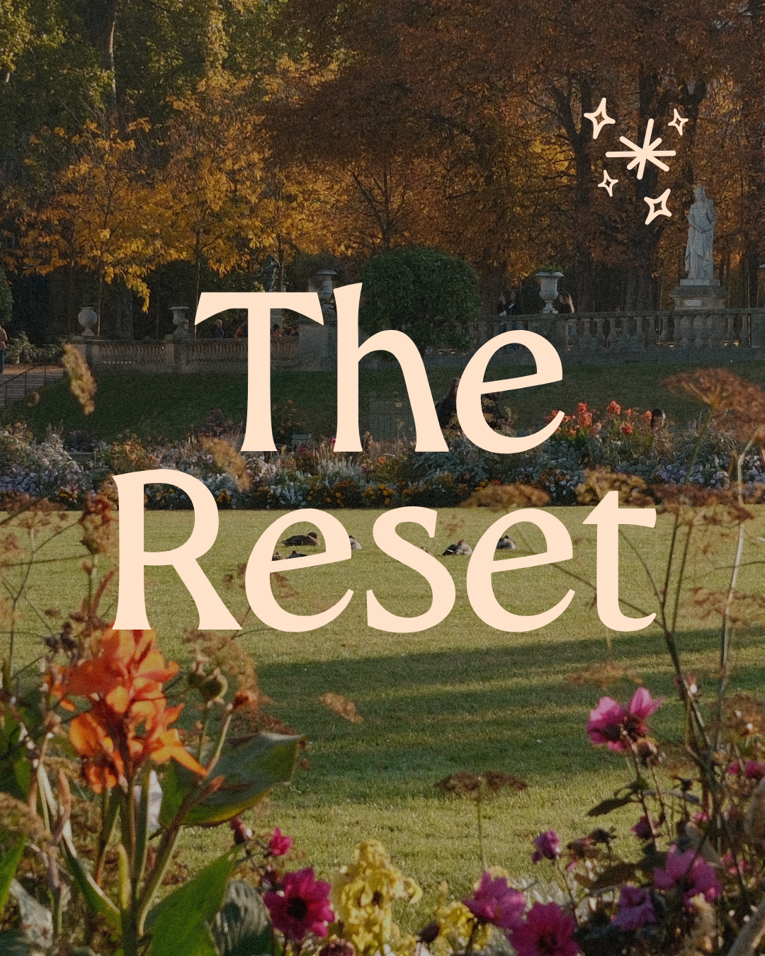 A park scene with a lawn, flower beds, trees with autumn leaves, and statues in the background. Overlaid text reads 'The Reset'.