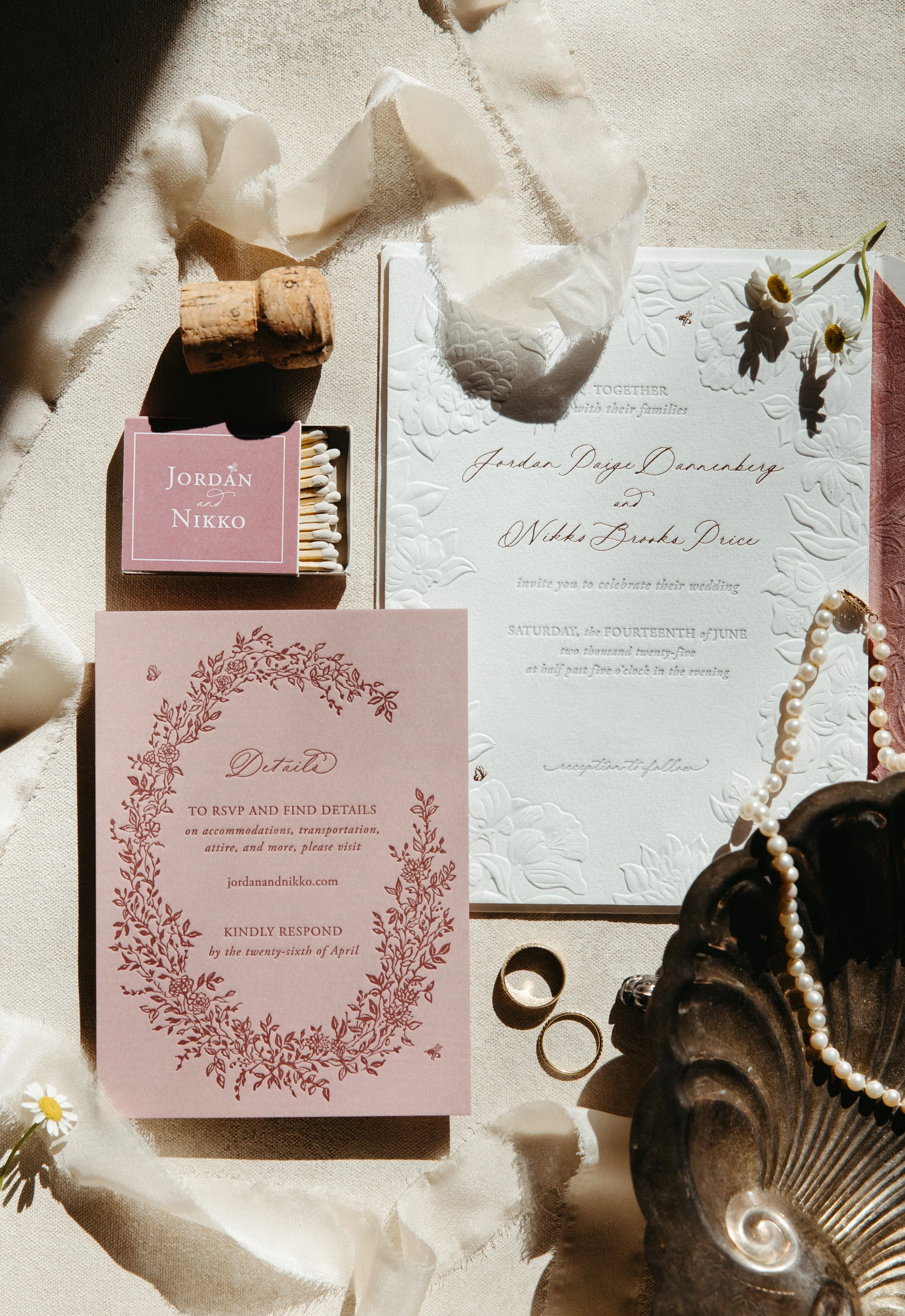 Wedding invitation suite styled with flowers, ribbon, and pearls.
