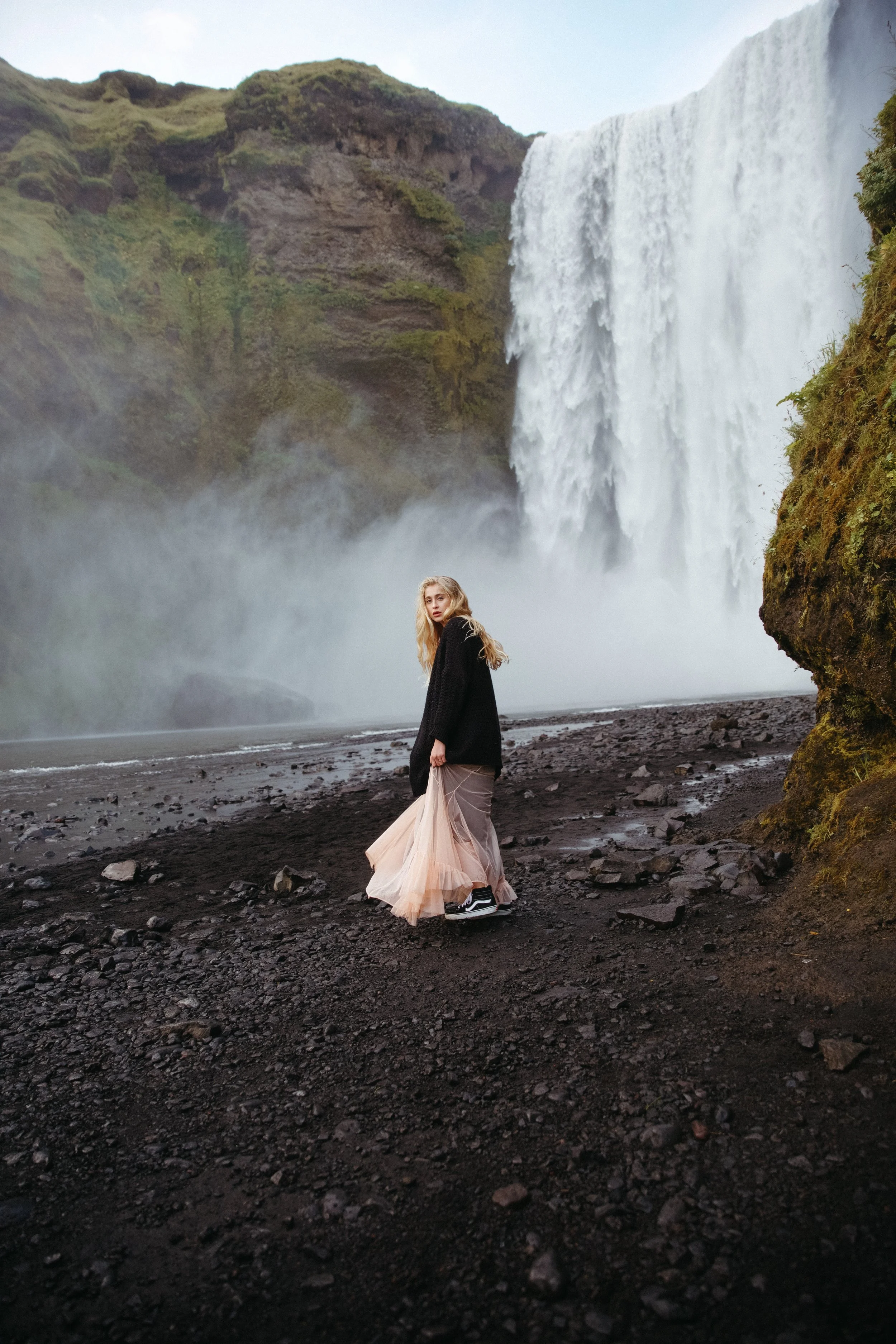 woman in dress by Skógafoss waterfall in iceland