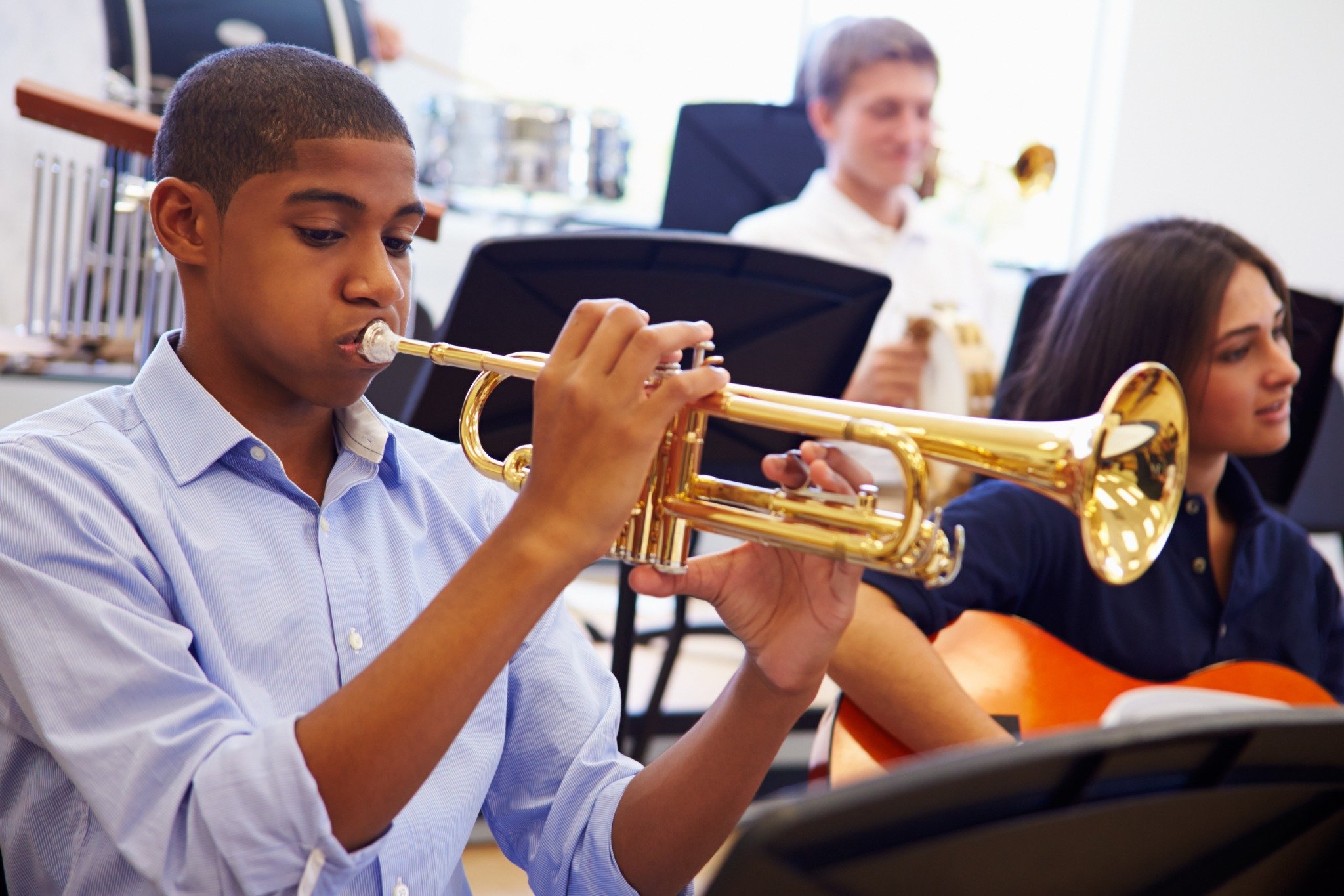 A teenage boy playing a trumpet in a band