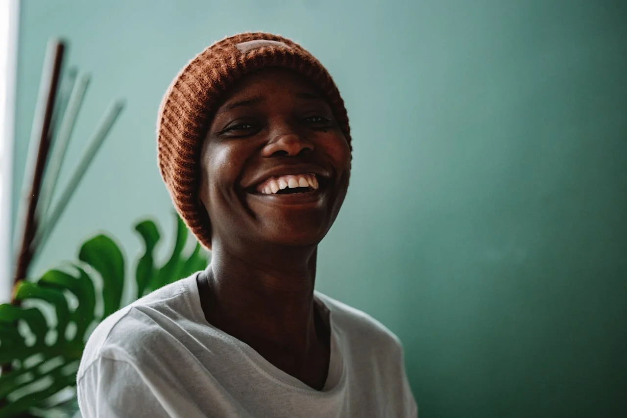 a-person-smiling-while-wearing-a-knitted-cap