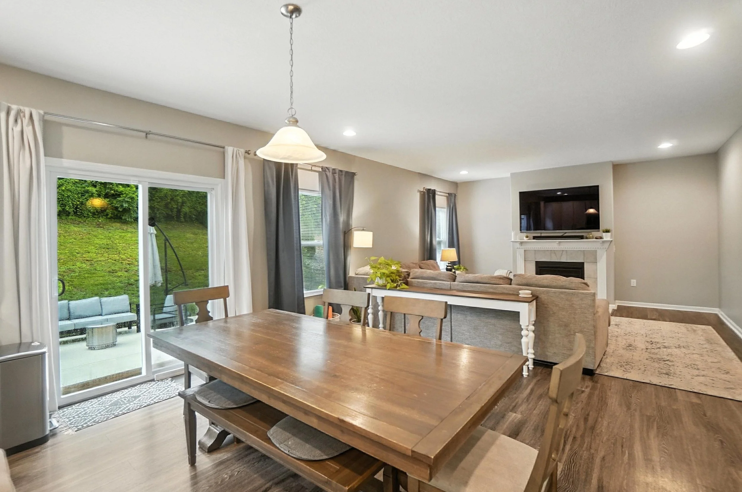 Open-concept living and dining area with hardwood floors, sliding glass door leading to patio, and a fireplace with mounted TV