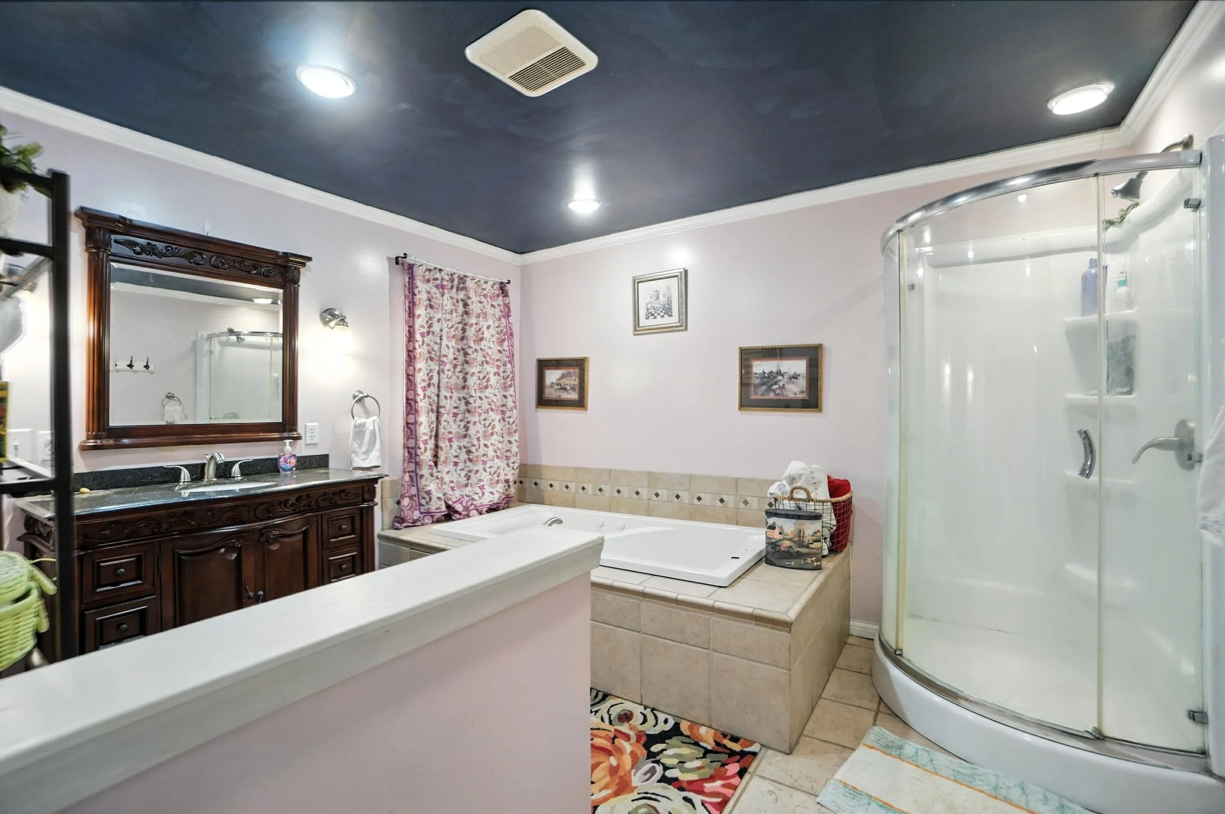 Bathroom with dark ceiling, white walls, a wooden vanity with a mirror, a bathtub, and a shower.