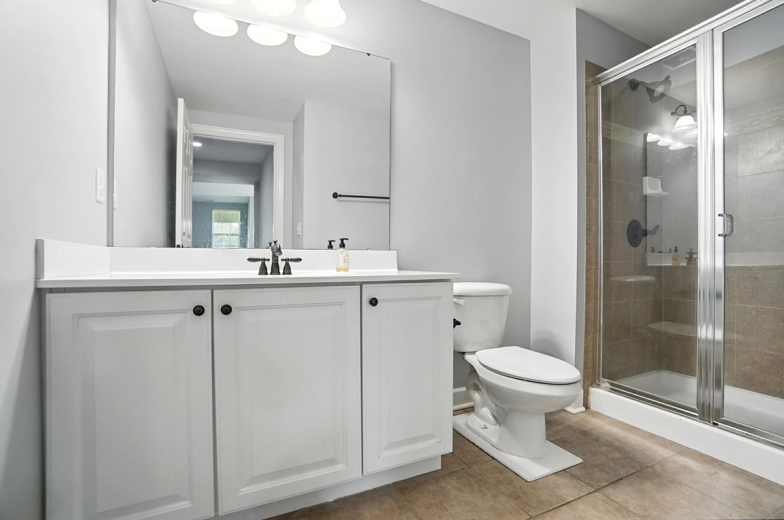 Modern bathroom with white vanity, toilet, and glass shower enclosure