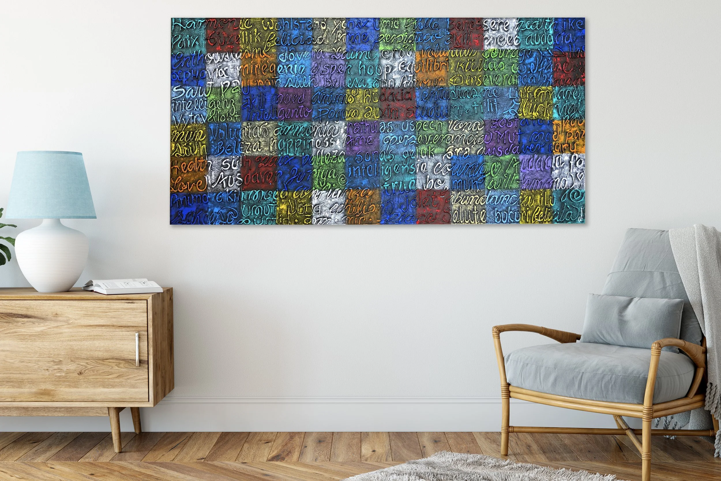 Colorful abstract wall art with handwritten words in various colors hanging above a light gray chair with wooden arms in a minimalist living room.