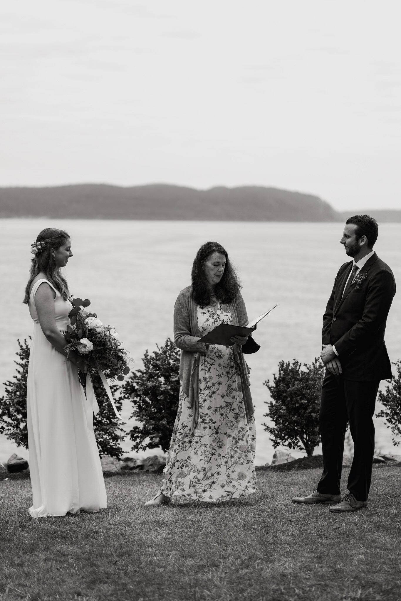 a man and woman stand in front of the ocean to get married
