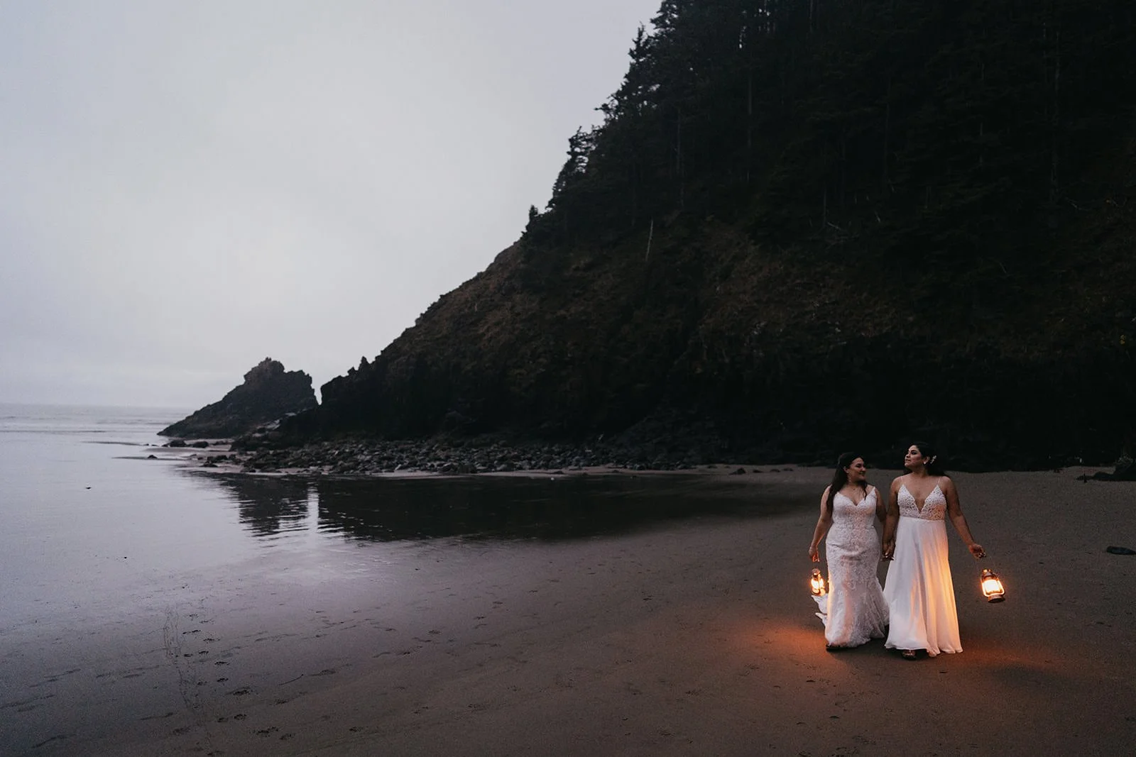 two brides with lanterns in their hands walk towards the camera on their elopement day