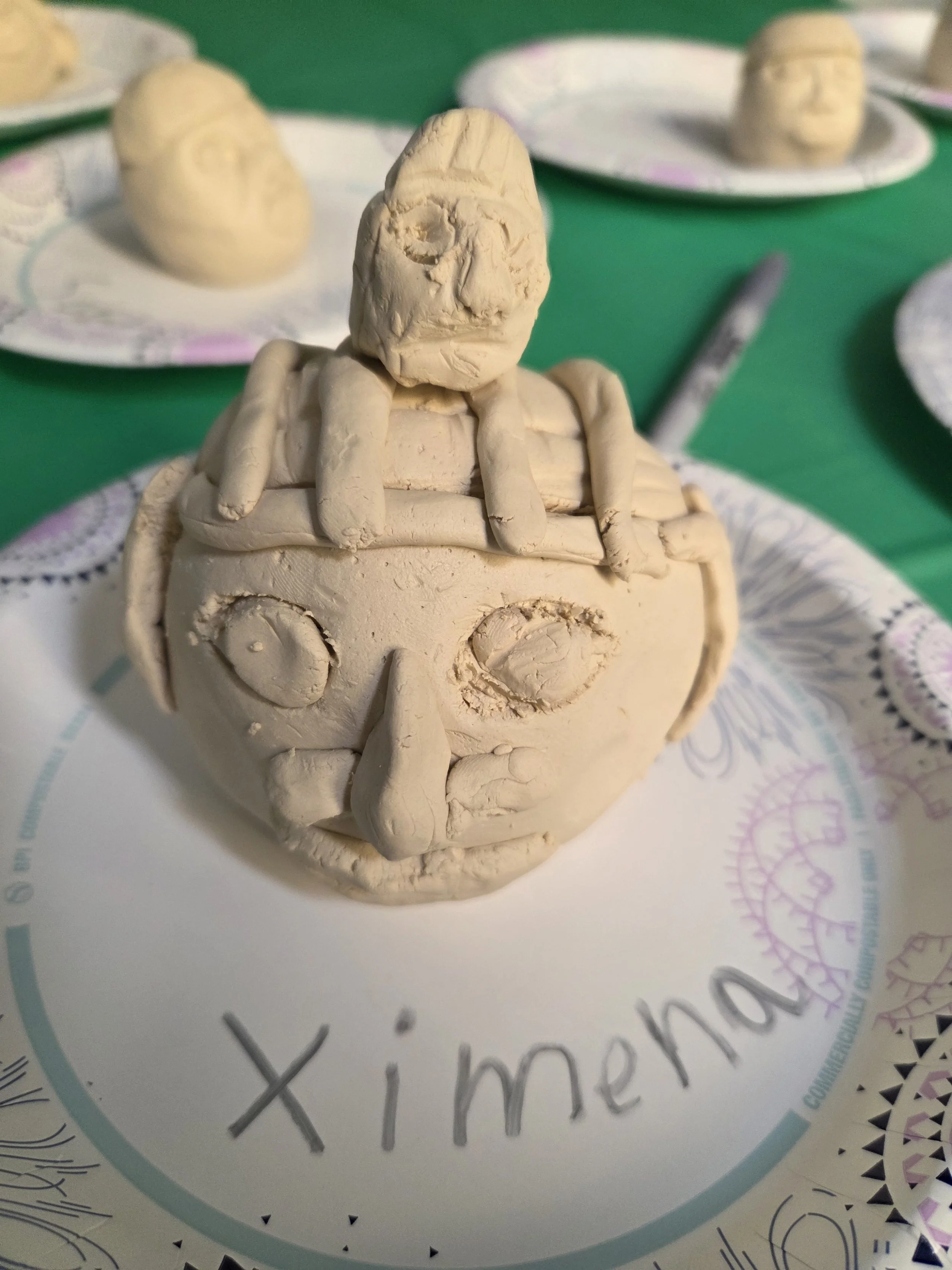 Youth-created clay Olmec head sculpture from a hands-on cultural education program.