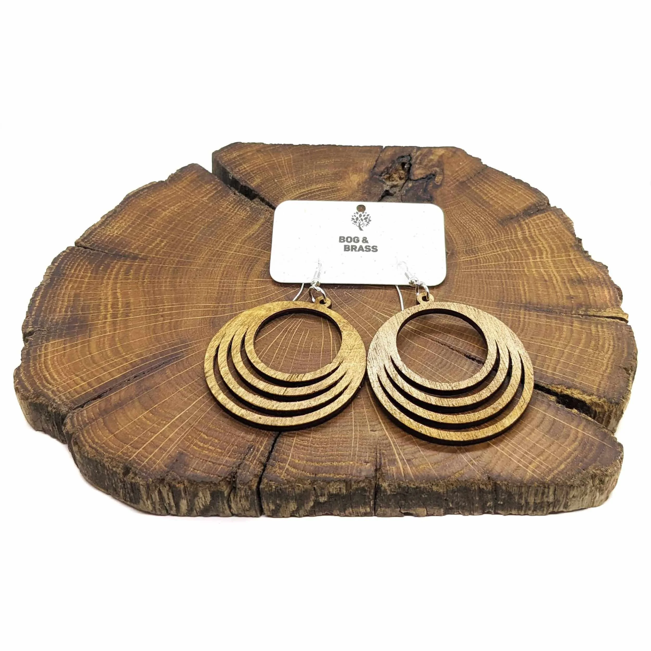 Wooden fanned earrings on a slice of wood.