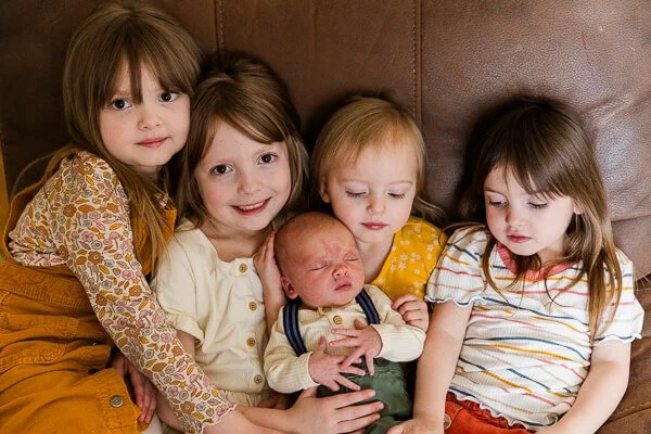 Four little girls hold newborn brother