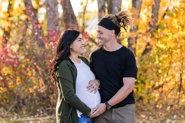 Expectant parents smile at each other as they touch mom's belly
