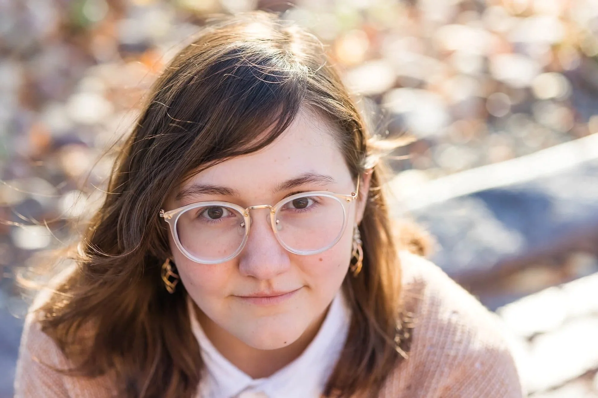 Teen girl with big glasses look up toward camera
