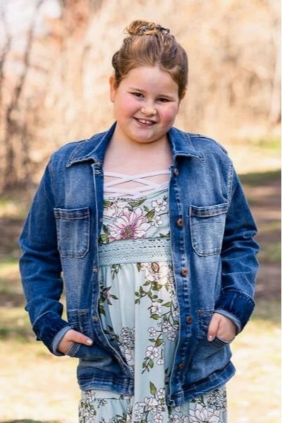 Smiling girl wearing denim jacket & flowered dress