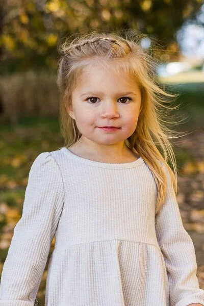 Little girl with braided hair wearing cream colored dress