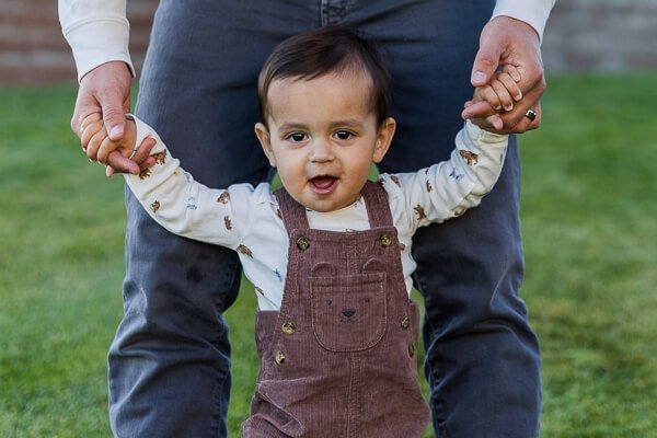 Toddler hangs on to parent's fingers