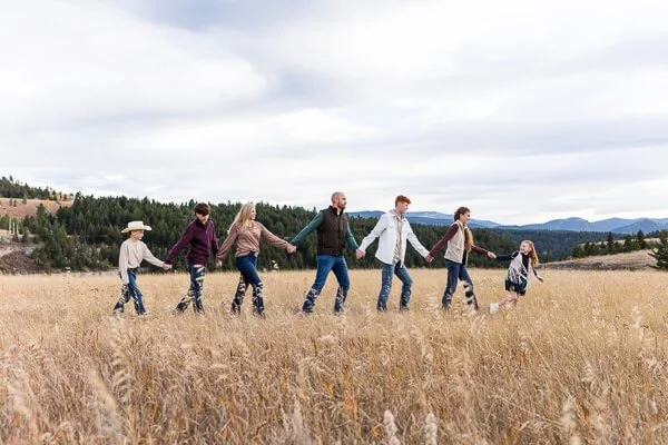 Family of 7 walks across meadow holding hands at Sluice Boxes State Park