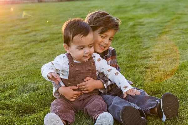 Little boy gives toddler
 brother a big hug