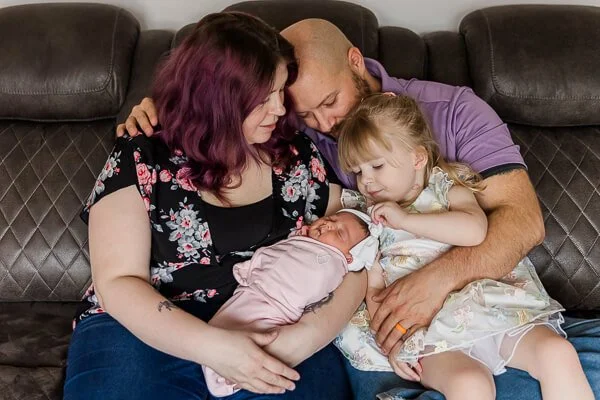 Photo of family of four with toddler touching newborn's hair bow at Great Falls, MT newborn session