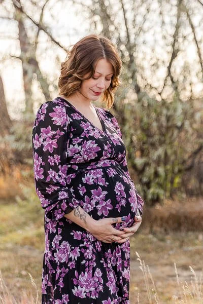 Pregnant woman wraps her hands around her belly and gazes down at her bump
