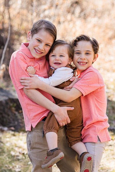 Two brothers hug toddler brother between them at Giant Springs State Park