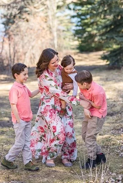 Mom holding toddler tickles son as another son looks on and laughs at Giant Springs State Park