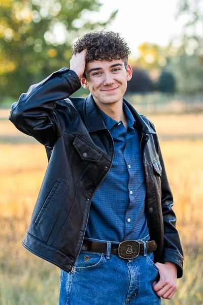 Senior in blue shirt & black leather jacket ruffles his hair