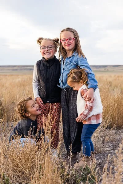 Four small child hang on to each other and laugh