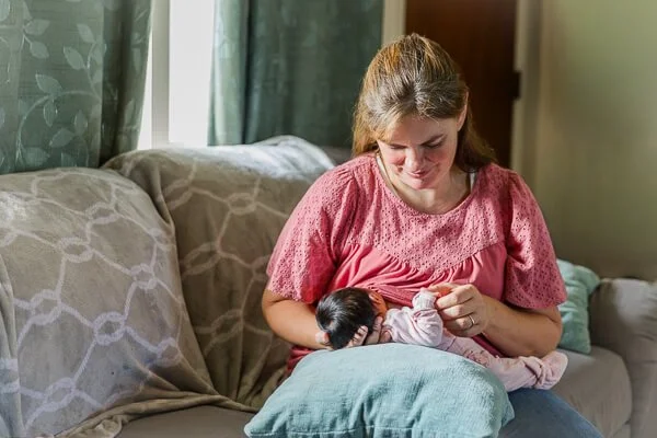 Mom gently touches newborn's hands as she nurses her