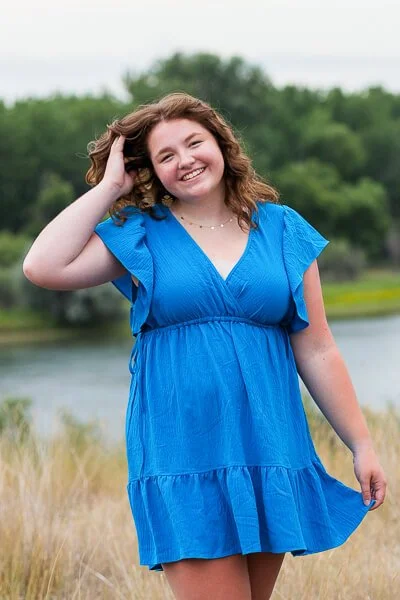 Senior girl wearing blue dress plays with her hair