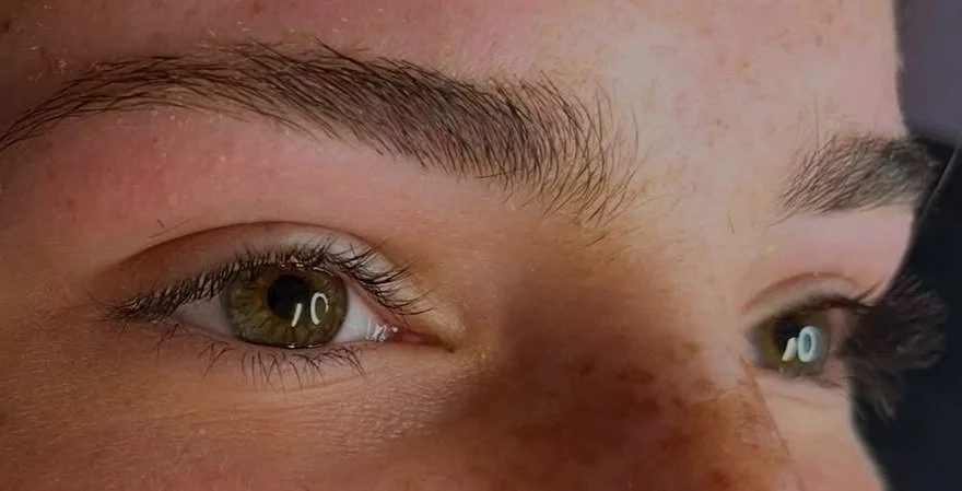 Close-up of a person's face focusing on their hazel eyes and freckles on their nose.