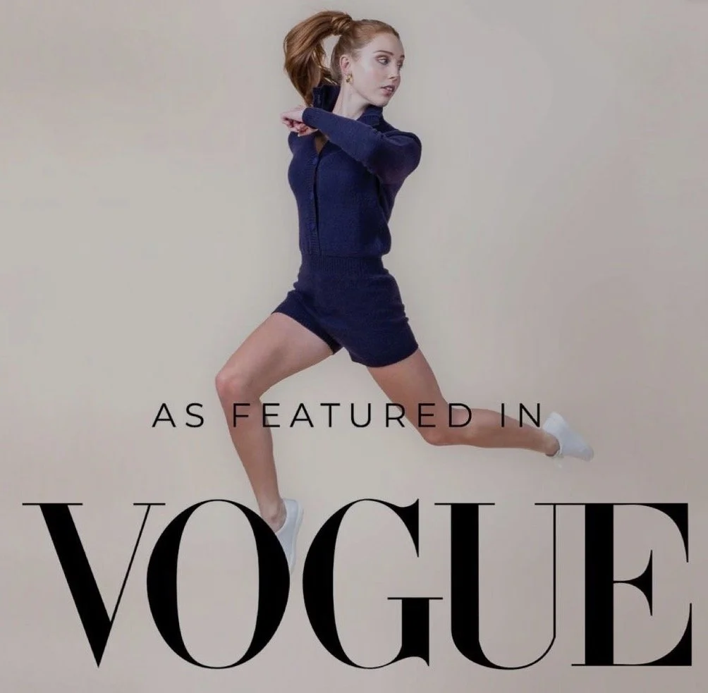 A woman in a navy blue athletic outfit, jumping with one knee bent, against a plain background, with text indicating she is featured in Vogue.