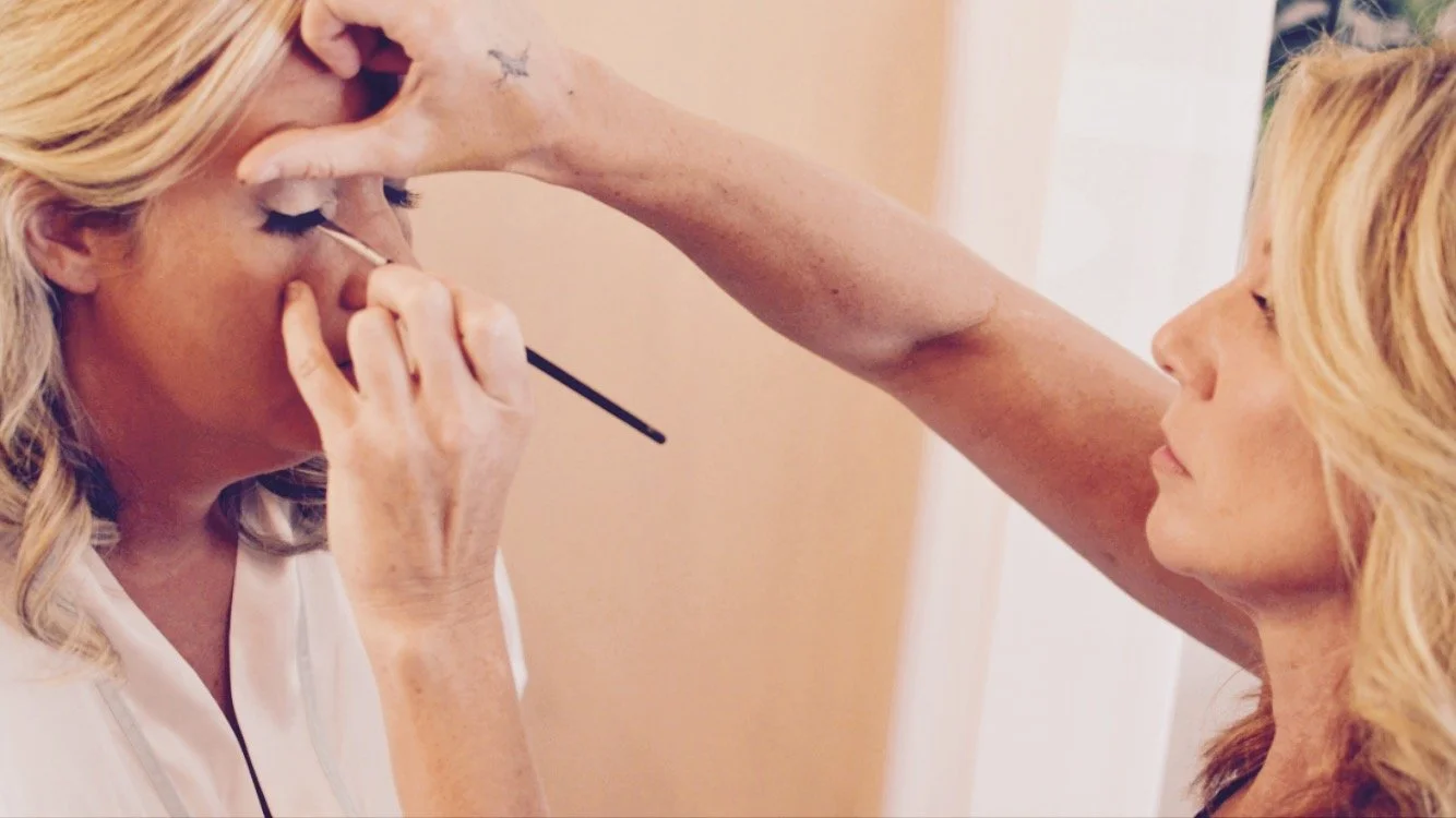 A woman getting her makeup applied by a makeup artist.