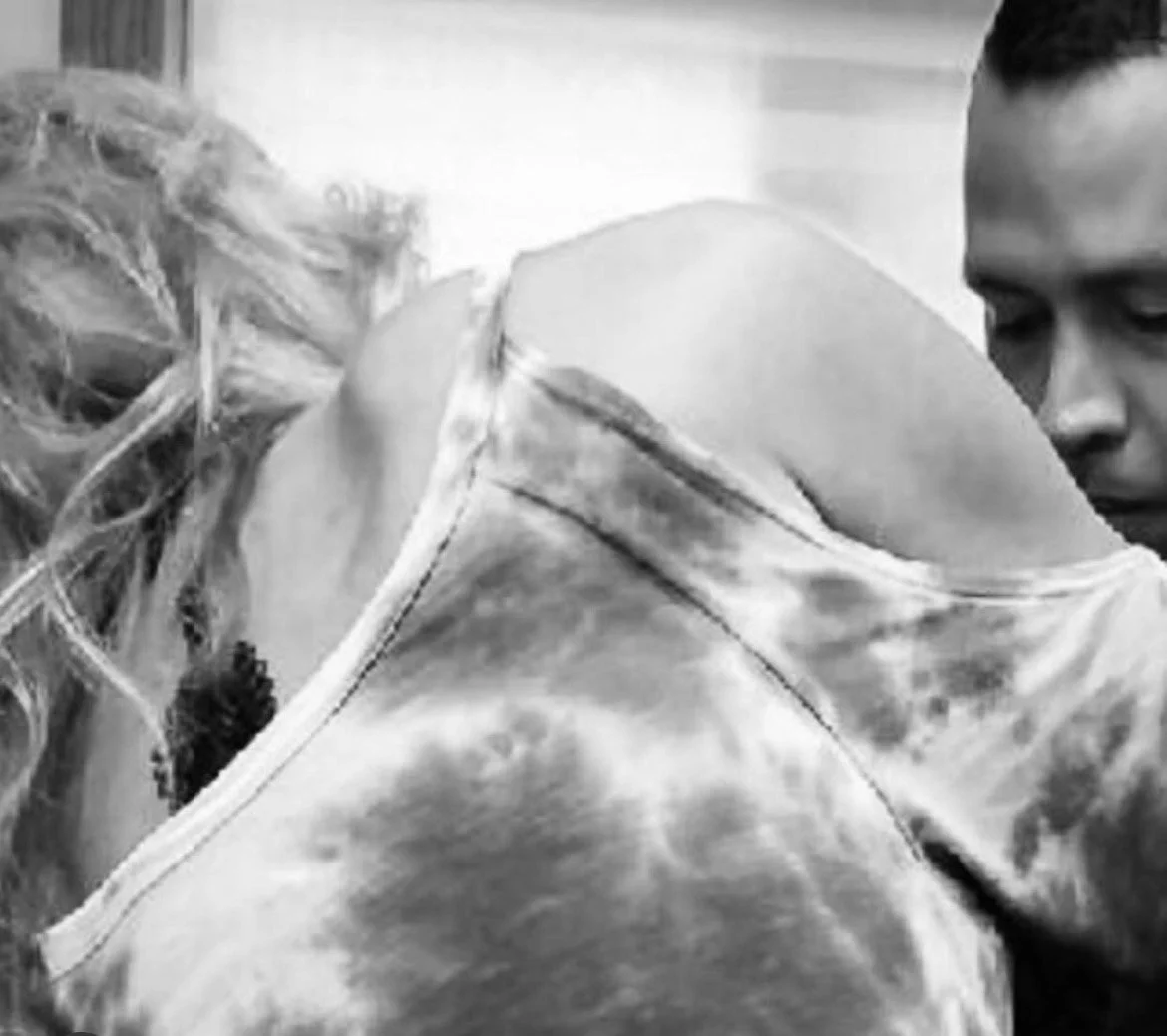 A close-up black and white photograph of a young man and woman in an intimate moment, with their heads close together.