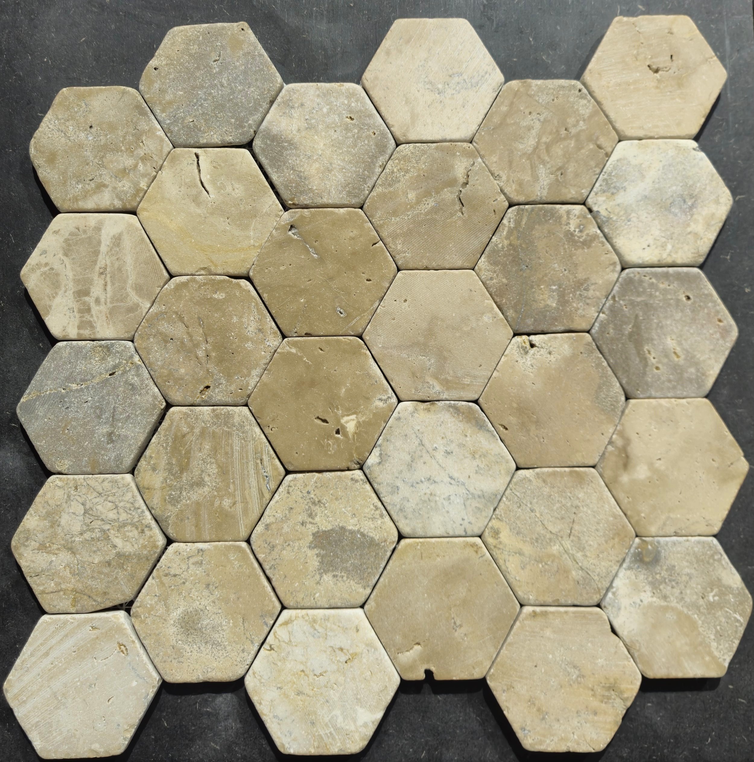 Bruine zeshoekige tegels in een honingraatpatroon gelegd op een donkere achtergrond.