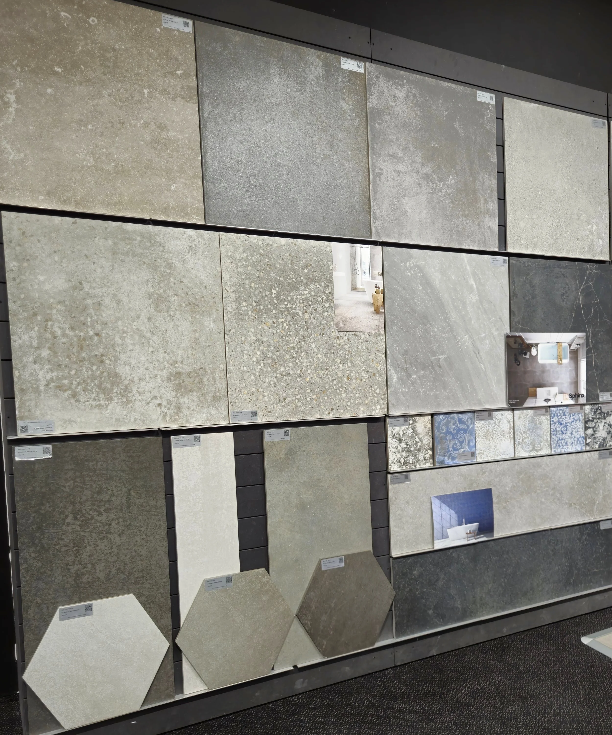 Een muur met een display van verschillende soorten en kleuren wand- en vloertegels in een winkel of showroom.